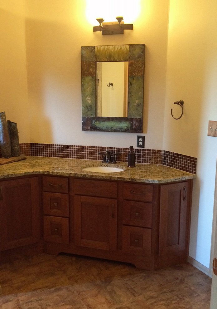 Exemple d'une grande salle de bain chic en bois brun avec un lavabo encastré, un placard à porte plane, un plan de toilette en granite, un carrelage marron, un carrelage en pâte de verre et un sol en linoléum.