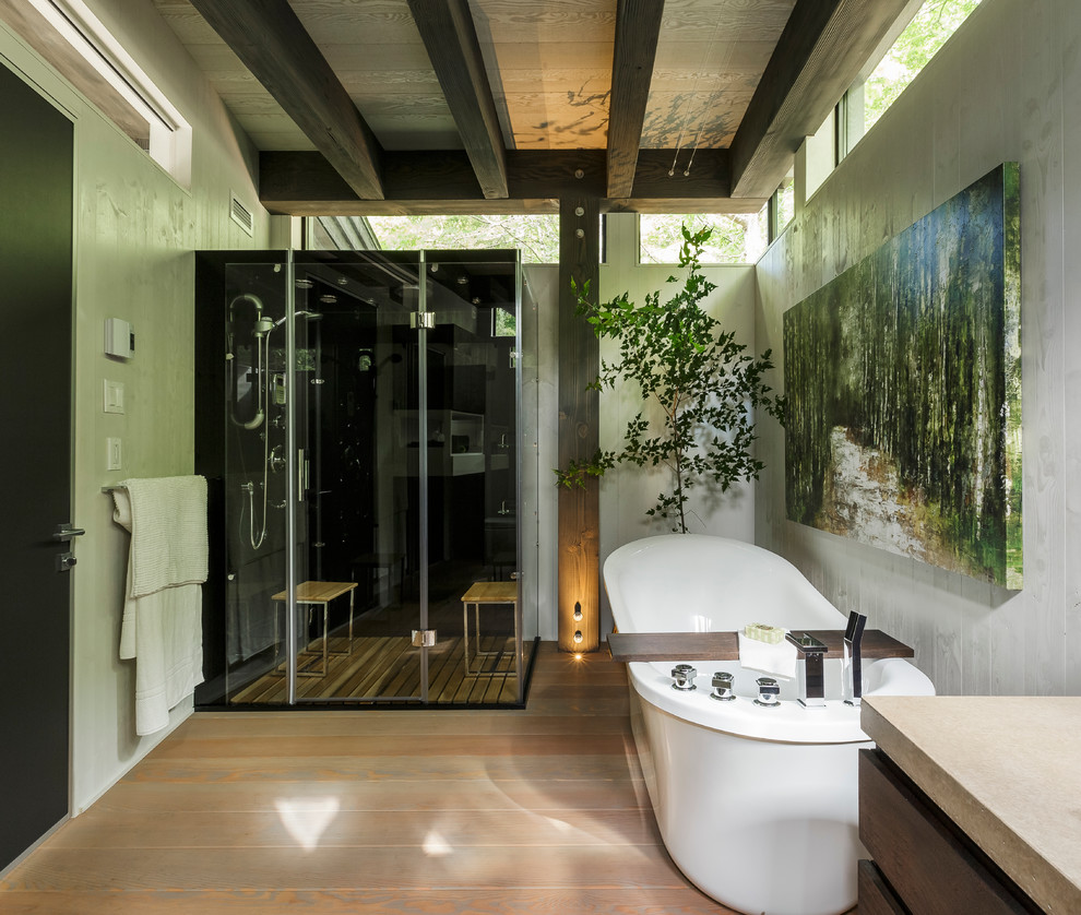Bild på ett funkis en-suite badrum, med ett fristående badkar, vita väggar och ljust trägolv