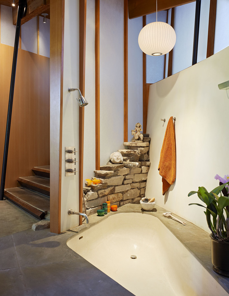 Réalisation d'une salle de bain design avec un carrelage de pierre et une baignoire encastrée.