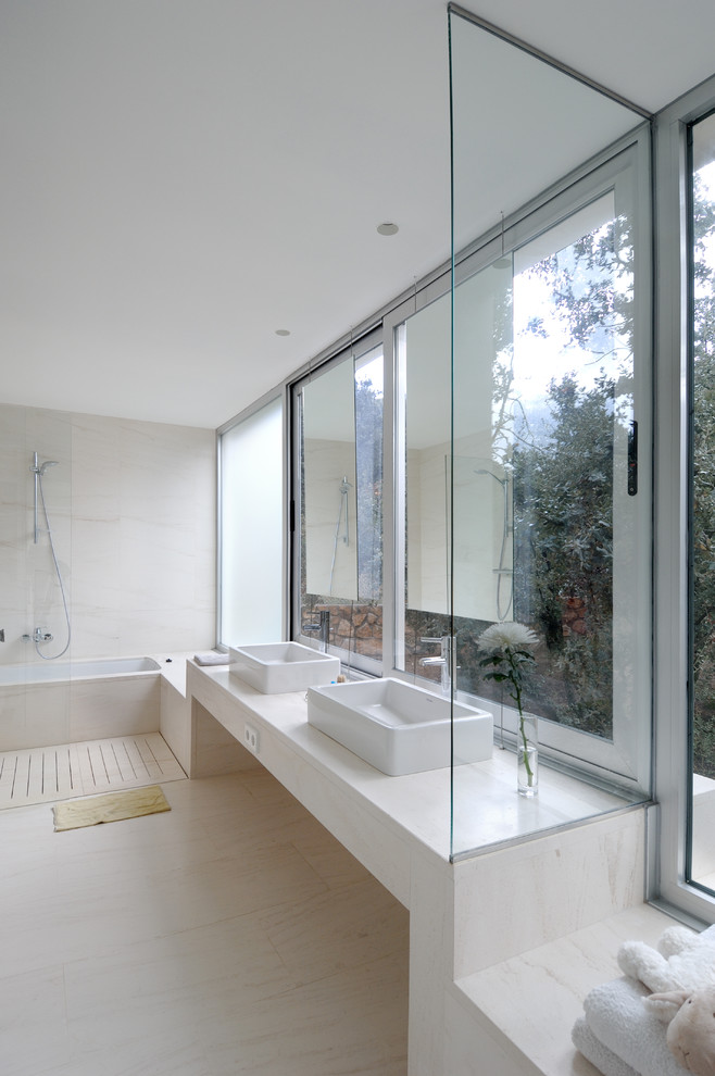 На фото: огромная ванная комната в современном стиле с ванной в нише, душем над ванной, белыми стенами и настольной раковиной с