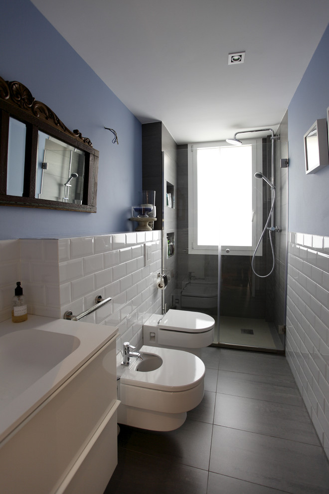Medium sized contemporary ensuite bathroom in Madrid with flat-panel cabinets, white cabinets, an alcove shower, a wall mounted toilet, white tiles, ceramic tiles, blue walls, ceramic flooring and an integrated sink.