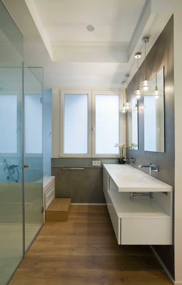 Foto de cuarto de baño largo y estrecho actual con lavabo integrado, armarios con paneles lisos y puertas de armario blancas