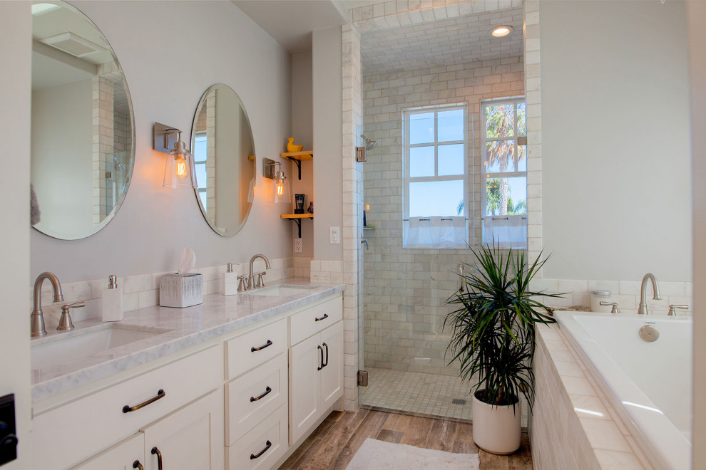 Inspiration for a mid-sized coastal master gray tile and marble tile porcelain tile and brown floor bathroom remodel in San Diego with shaker cabinets, white cabinets, a two-piece toilet, gray walls, an undermount sink, quartz countertops, a hinged shower door and white countertops