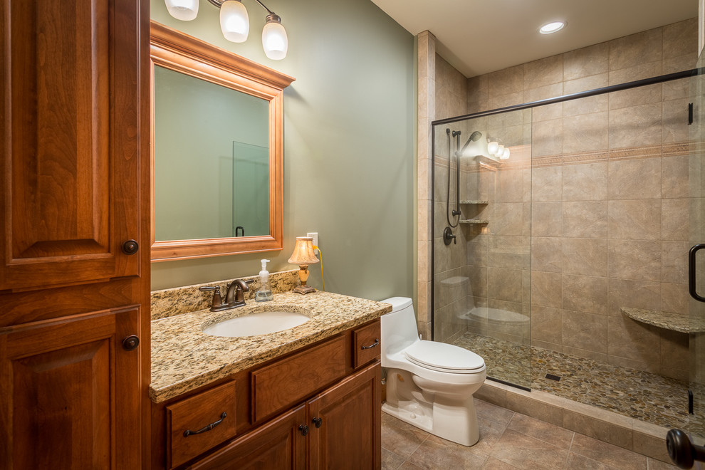 Cette photo montre une salle de bain montagne en bois brun de taille moyenne avec un lavabo encastré, un placard avec porte à panneau surélevé, un plan de toilette en granite, un carrelage beige, des carreaux de céramique, un mur vert et un sol en carrelage de céramique.