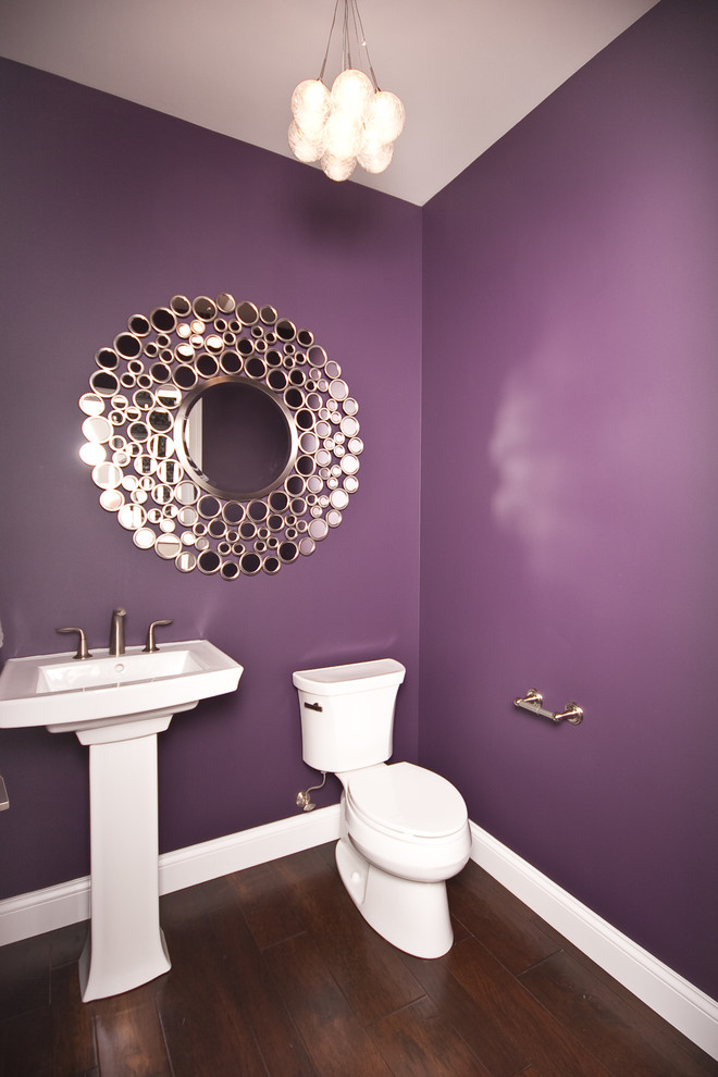 Inspiration för ett funkis badrum, med ett piedestal handfat, en toalettstol med separat cisternkåpa, lila väggar och mörkt trägolv