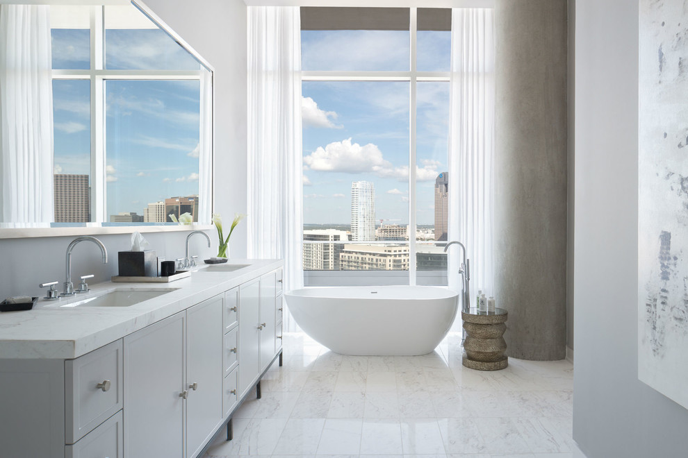 На фото: большая главная ванная комната в стиле модернизм с врезной раковиной, фасадами с утопленной филенкой, белыми фасадами, мраморной столешницей, белой плиткой, серыми стенами и мраморным полом с