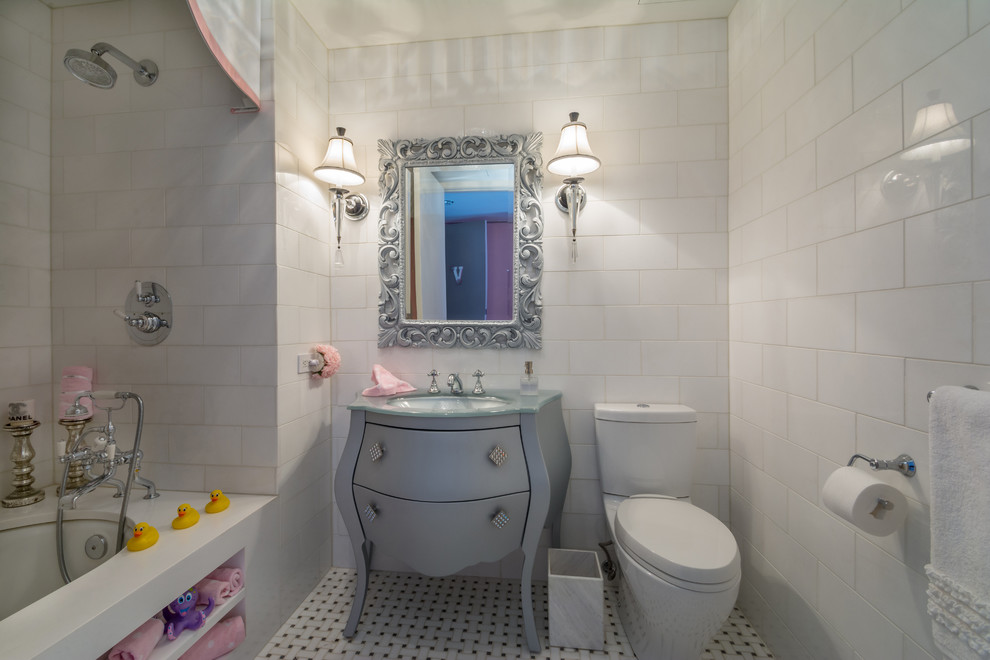 Immagine di una stanza da bagno per bambini shabby-chic style di medie dimensioni con pareti bianche, pavimento con piastrelle in ceramica, consolle stile comò, ante grigie, vasca ad alcova, vasca/doccia, WC a due pezzi, piastrelle bianche, piastrelle diamantate, lavabo sottopiano, top in vetro, pavimento multicolore e doccia con tenda