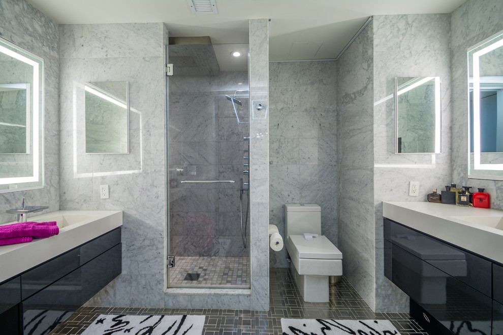 Inspiration for a medium sized contemporary ensuite bathroom in New York with flat-panel cabinets, grey cabinets, an alcove shower, a two-piece toilet, black and white tiles, grey tiles, stone slabs, ceramic flooring, an integrated sink, solid surface worktops and a hinged door.