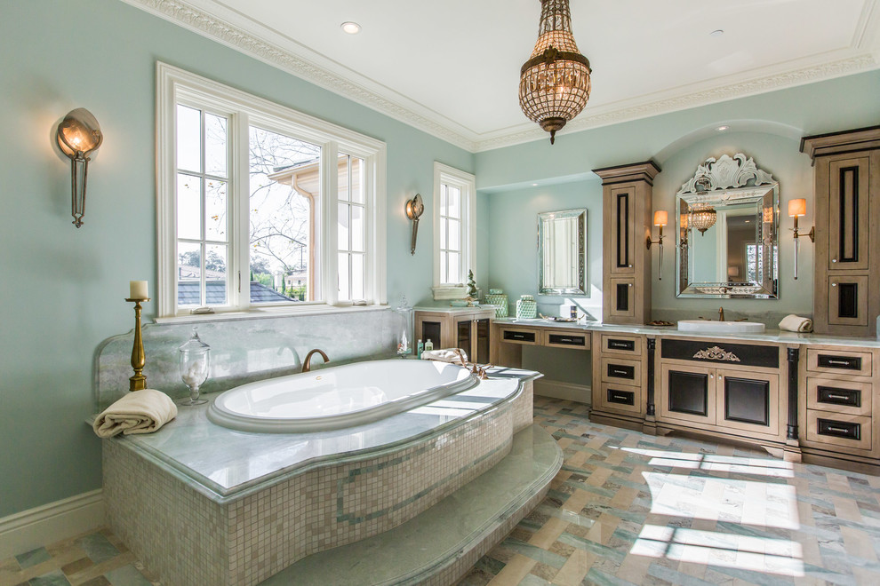 На фото: ванная комната в средиземноморском стиле с фасадами с утопленной филенкой, фасадами цвета дерева среднего тона, накладной ванной, синими стенами, накладной раковиной, разноцветным полом и зеленой столешницей с