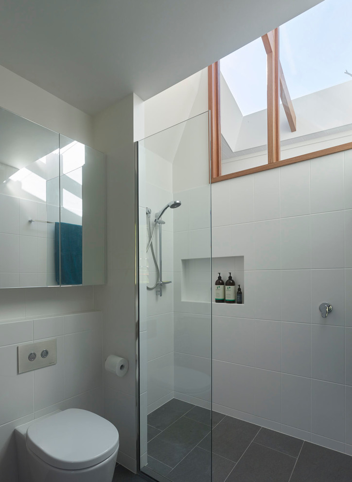 Small contemporary ensuite bathroom in Brisbane with light wood cabinets, a walk-in shower, a wall mounted toilet, white tiles, ceramic tiles, white walls, ceramic flooring, an integrated sink and solid surface worktops.