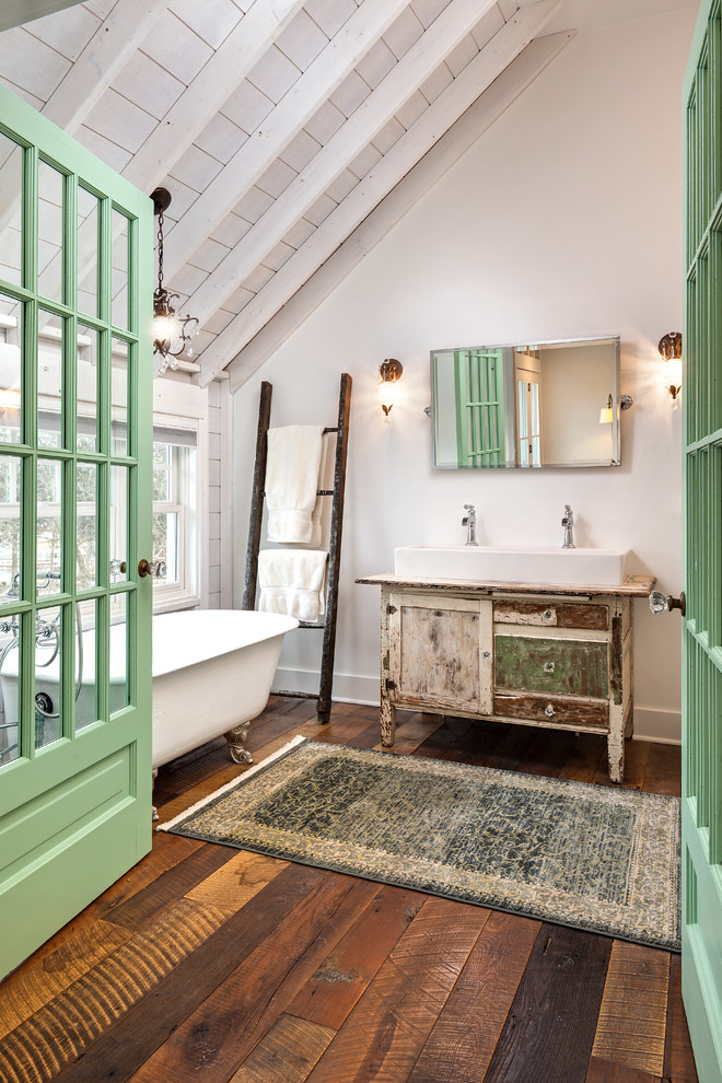 Inredning av ett eklektiskt badrum, med ett badkar med tassar, vita väggar, mellanmörkt trägolv och träbänkskiva