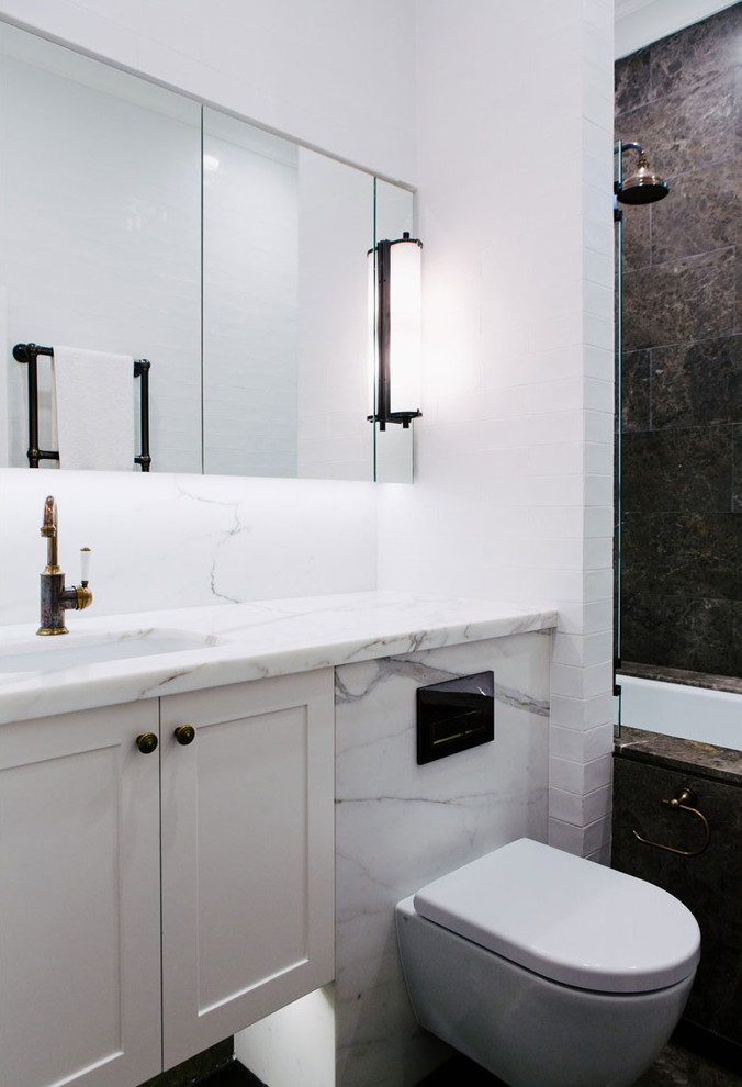 На фото: ванная комната в стиле неоклассика (современная классика) с полновстраиваемой ванной, унитазом-моноблоком, коричневой плиткой, белыми стенами, мраморной столешницей, душем над ванной и врезной раковиной с