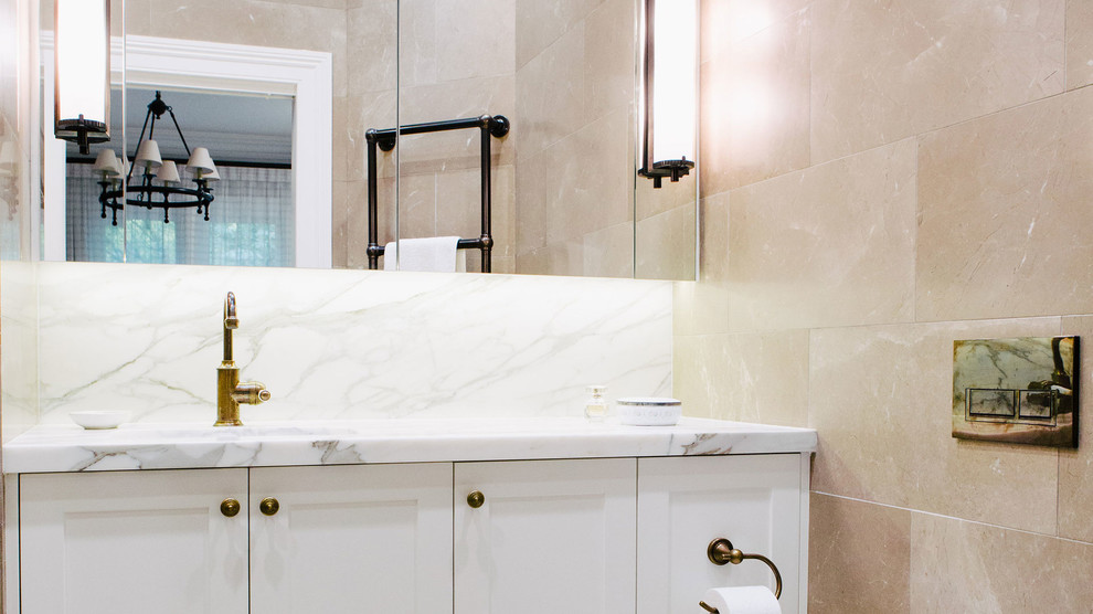 Idée de décoration pour une salle de bain vintage avec un placard à porte shaker, des portes de placard blanches, WC à poser, un carrelage beige, un mur beige et un plan de toilette en marbre.