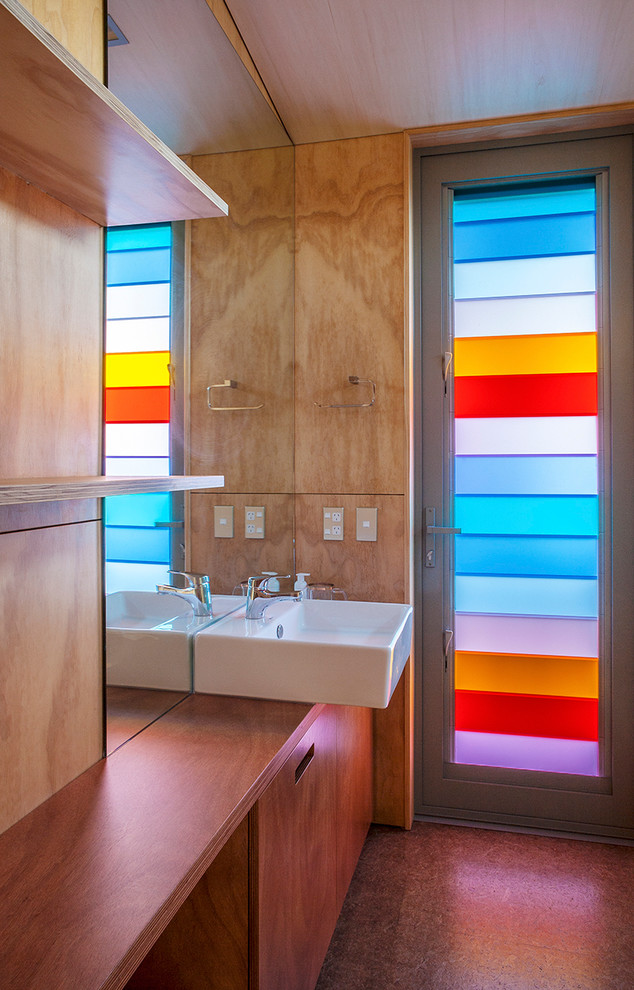 Trendy bathroom photo in Auckland with wood countertops, a vessel sink, flat-panel cabinets and medium tone wood cabinets