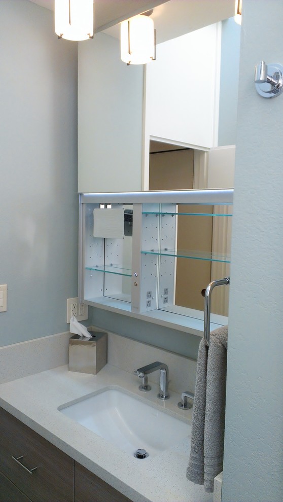 Diseño de cuarto de baño actual pequeño con armarios con paneles lisos, puertas de armario de madera oscura, paredes azules, aseo y ducha, lavabo encastrado y encimera de laminado