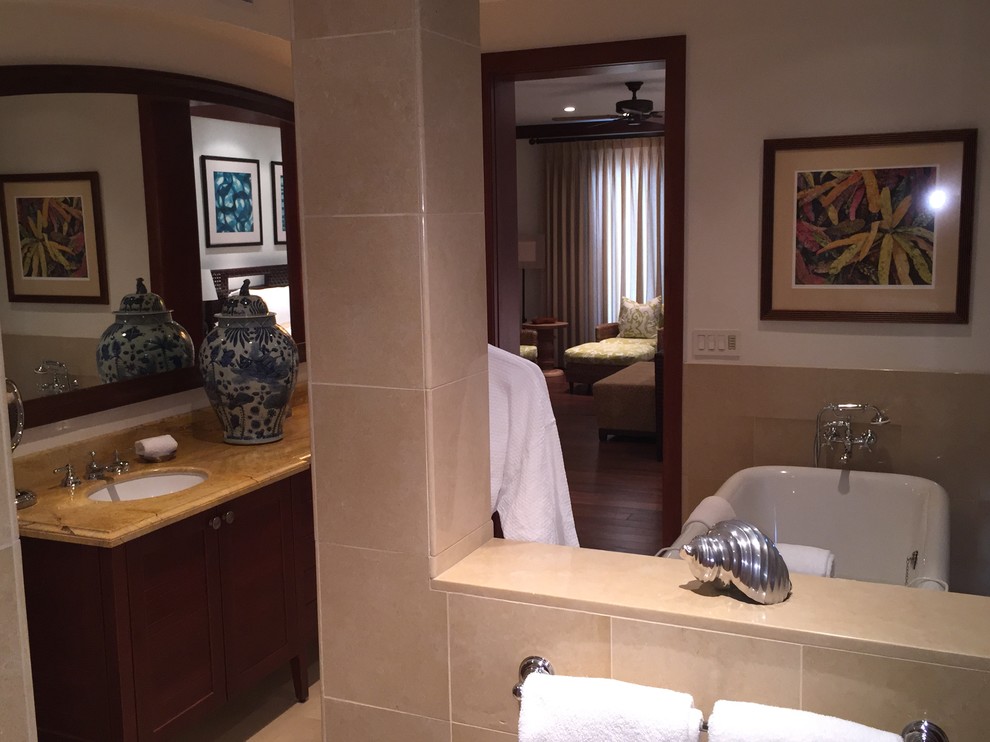 ハワイにある高級な広いトラディショナルスタイルのおしゃれなマスターバスルーム (アンダーカウンター洗面器、落し込みパネル扉のキャビネット、濃色木目調キャビネット、大理石の洗面台、置き型浴槽、コーナー設置型シャワー、分離型トイレ、ベージュのタイル、石タイル、白い壁、ライムストーンの床) の写真
