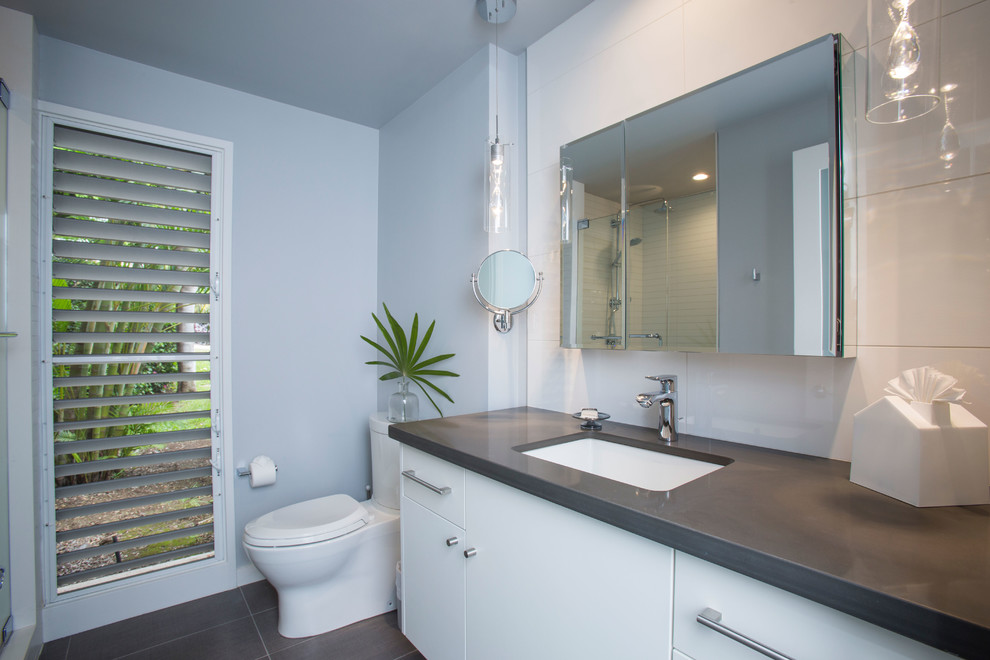 Traditional bathroom in Hawaii with flat-panel cabinets, white cabinets, a walk-in shower, white tiles, porcelain tiles, grey walls, porcelain flooring, a submerged sink and engineered stone worktops.