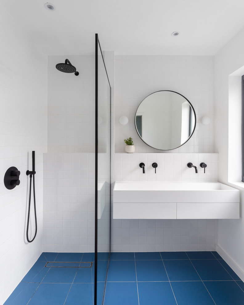 Inspiration pour une salle de bain design avec un placard à porte plane, des portes de placard blanches, une douche à l'italienne, un carrelage blanc, un plan vasque, un sol bleu et aucune cabine.