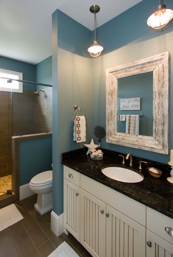 Cette image montre une douche en alcôve marine avec un lavabo encastré, un placard avec porte à panneau encastré, des portes de placard beiges et un carrelage marron.