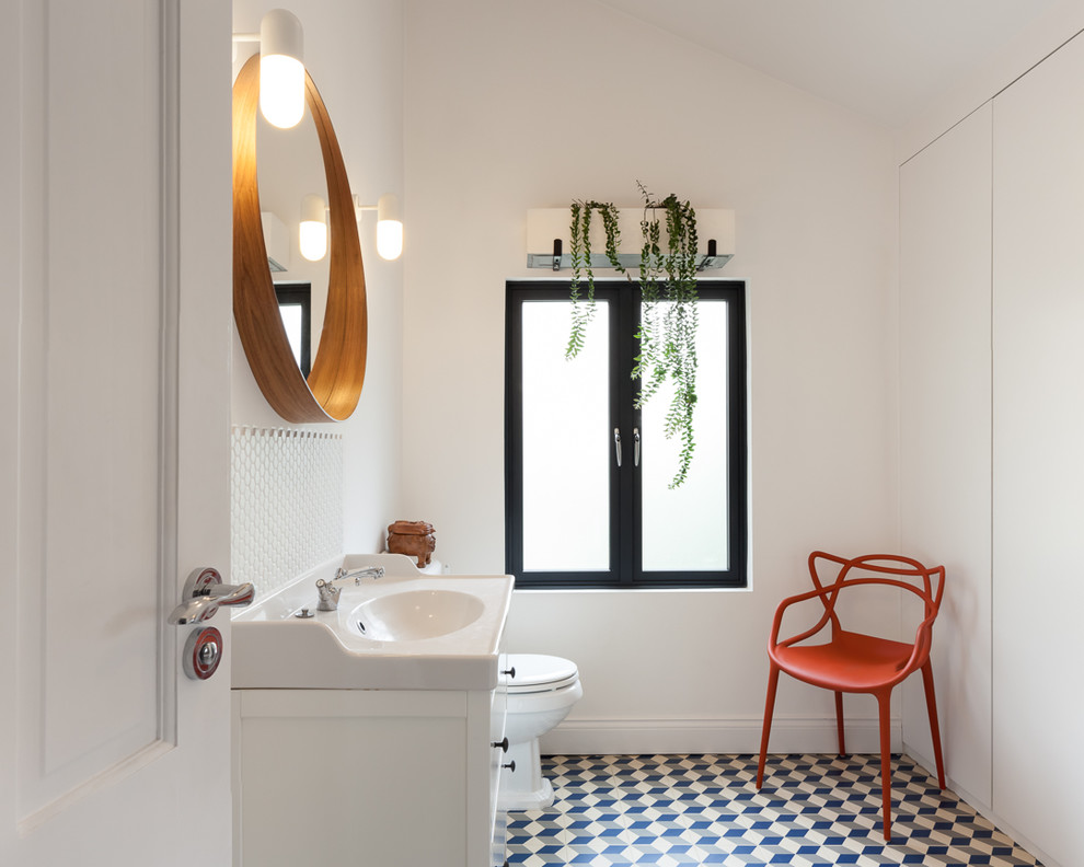 Esempio di una stanza da bagno minimal di medie dimensioni con WC a due pezzi, pareti bianche, pavimento in cementine, lavabo a consolle, pavimento multicolore e ante bianche