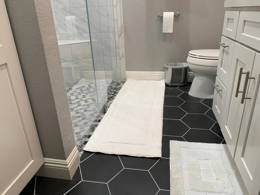 Esempio di una stanza da bagno minimalista con doccia a filo pavimento, WC monopezzo, piastrelle bianche, pareti grigie, pavimento nero e porta doccia scorrevole