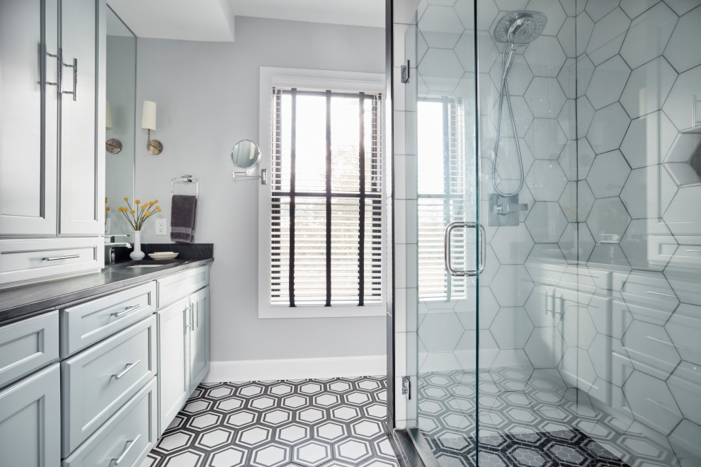 This is an example of a large classic family bathroom in St Louis with freestanding cabinets, blue cabinets, a built-in shower, a two-piece toilet, black and white tiles, mosaic tiles, grey walls, terracotta flooring, a submerged sink, soapstone worktops, black floors, a hinged door and black worktops.