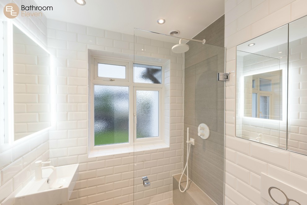 This is an example of a contemporary ensuite wet room bathroom with a one-piece toilet, white tiles, ceramic tiles, grey walls, a trough sink, ceramic flooring, white cabinets, solid surface worktops, beige floors, an open shower and white worktops.