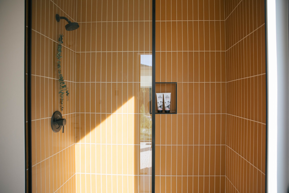 Minimalistisk inredning av ett badrum, med gul kakel och glaskakel