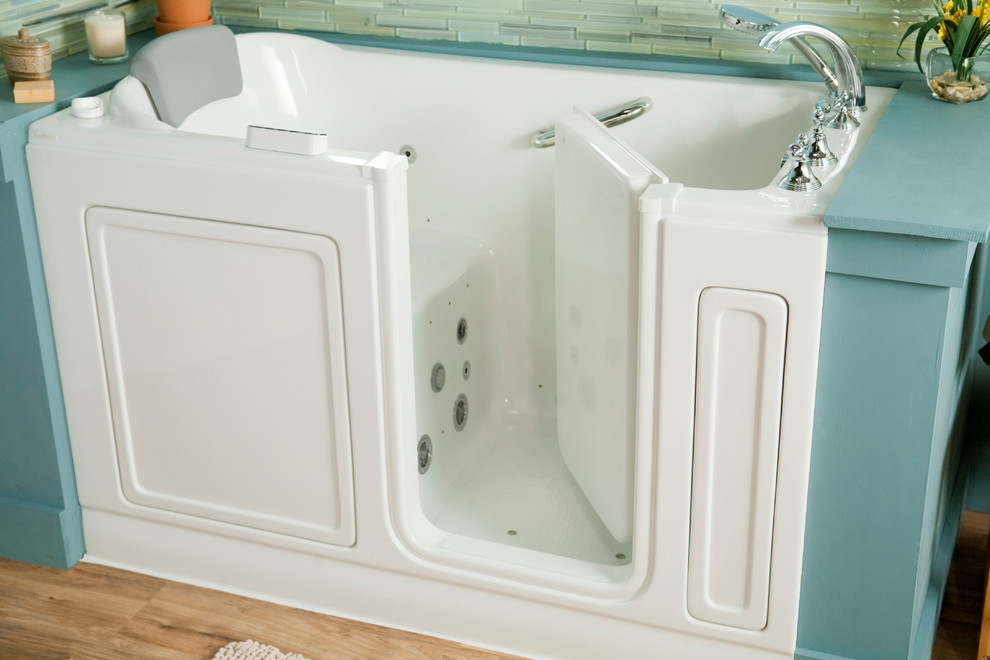 Exempel på ett mellanstort klassiskt en-suite badrum, med ett badkar i en alkov, en dusch/badkar-kombination, en toalettstol med separat cisternkåpa, beige kakel, stickkakel, blå väggar, ljust trägolv, ett piedestal handfat, brunt golv och dusch med gångjärnsdörr