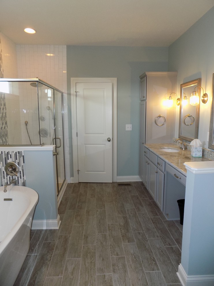 Bathroom - mid-sized craftsman master white tile and ceramic tile cement tile floor and brown floor bathroom idea in Columbus with recessed-panel cabinets, gray cabinets, a two-piece toilet, blue walls, an undermount sink, granite countertops and a hinged shower door
