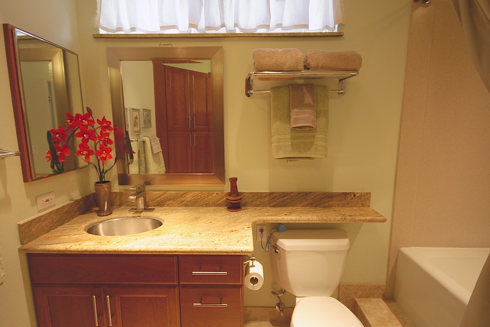 Mid-sized trendy beige tile and porcelain tile porcelain tile bathroom photo in Hawaii with a vessel sink, recessed-panel cabinets, medium tone wood cabinets, granite countertops, a two-piece toilet and white walls