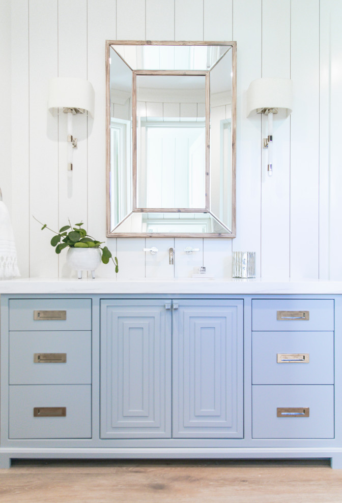 Idee per una stanza da bagno padronale costiera con ante blu, doccia alcova, parquet chiaro, porta doccia a battente e top bianco
