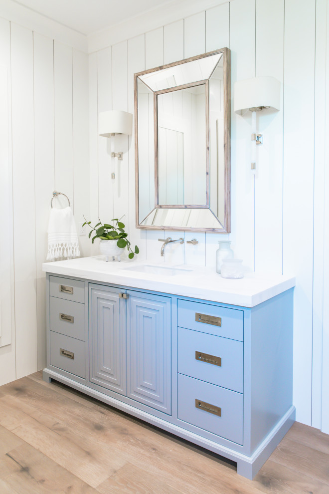 Beach style master light wood floor, beige floor, single-sink and shiplap wall bathroom photo in San Diego with blue cabinets, white countertops, flat-panel cabinets, white walls, an undermount sink and a built-in vanity