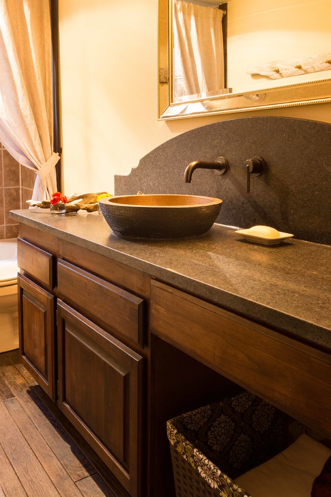 Foto di una stanza da bagno american style di medie dimensioni con ante con bugna sagomata, ante in legno scuro, top in granito, WC monopezzo, pareti gialle, parquet scuro e lavabo a bacinella