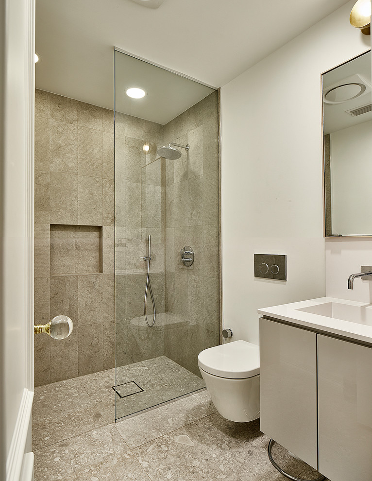 ダラスにあるラグジュアリーな中くらいなモダンスタイルのおしゃれな浴室 (フラットパネル扉のキャビネット、グレーのキャビネット、バリアフリー、壁掛け式トイレ、青いタイル、ガラス板タイル、白い壁、セラミックタイルの床、一体型シンク、珪岩の洗面台、置き型浴槽、白い床、開き戸のシャワー) の写真
