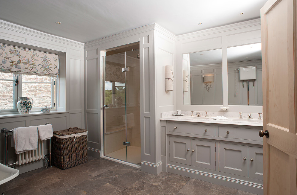 Foto de cuarto de baño principal clásico de tamaño medio con lavabo bajoencimera, puertas de armario grises, encimera de mármol, bañera exenta, ducha doble y paredes grises