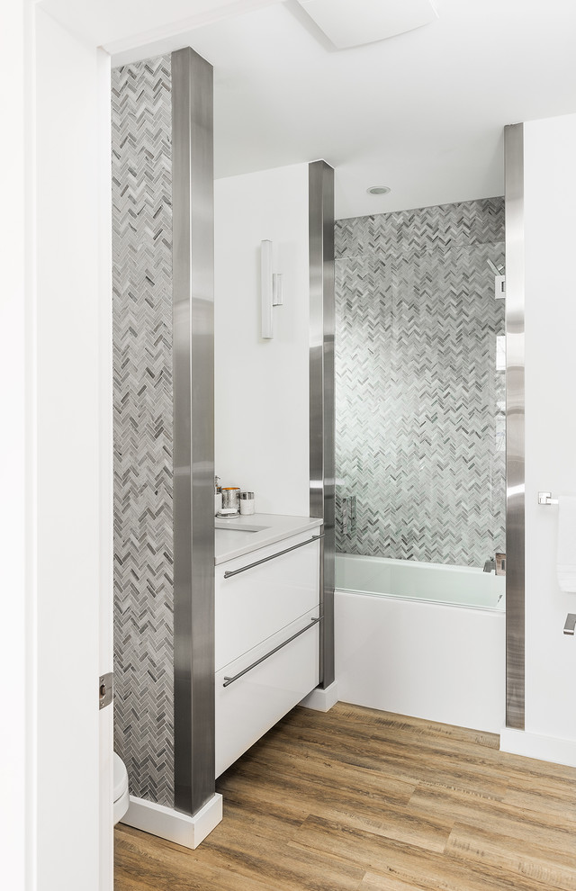 Свежая идея для дизайна: ванная комната в современном стиле с плоскими фасадами, белыми фасадами, ванной в нише, серой плиткой, плиткой мозаикой, белыми стенами, паркетным полом среднего тона, врезной раковиной, коричневым полом и белой столешницей - отличное фото интерьера
