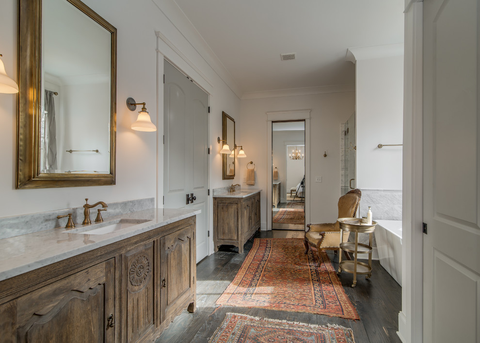 Imagen de cuarto de baño largo y estrecho tradicional renovado con lavabo bajoencimera, puertas de armario de madera oscura, bañera exenta, ducha empotrada y armarios con paneles con relieve