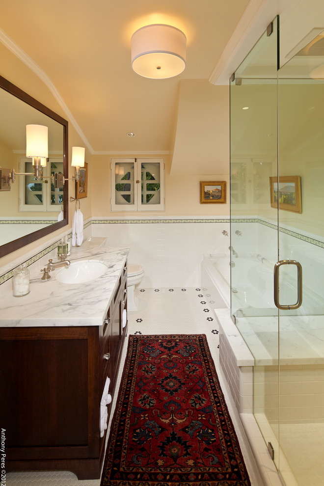 Inredning av ett klassiskt mellanstort badrum med dusch, med skåp i shakerstil, skåp i mörkt trä, ett hörnbadkar, en hörndusch, vit kakel, porslinskakel, beige väggar, klinkergolv i porslin, ett undermonterad handfat, marmorbänkskiva, vitt golv och dusch med gångjärnsdörr