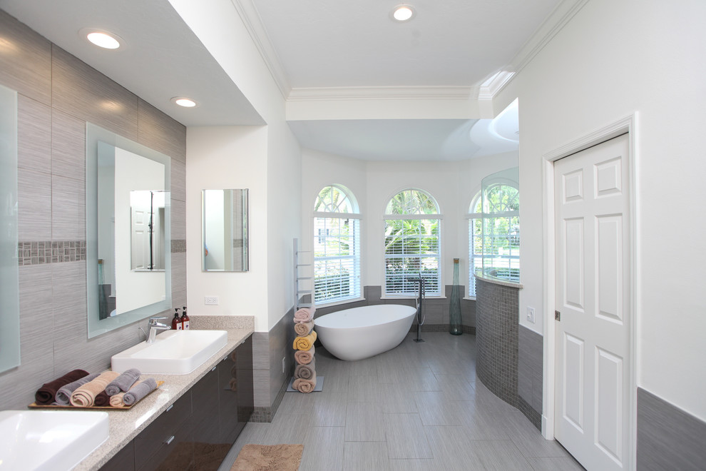 Exempel på ett mellanstort modernt en-suite badrum, med grå kakel, ett fristående handfat, släta luckor, grå skåp, bänkskiva i onyx, ett fristående badkar, en öppen dusch, porslinskakel, vita väggar och klinkergolv i porslin