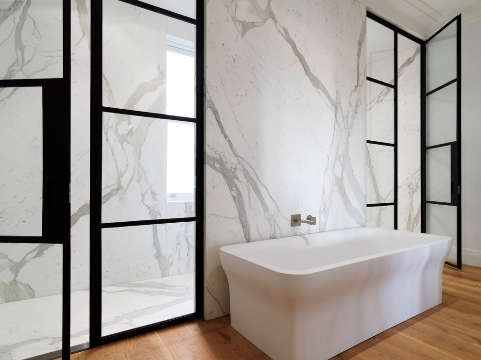 Diseño de cuarto de baño actual con bañera exenta, baldosas y/o azulejos blancos y losas de piedra