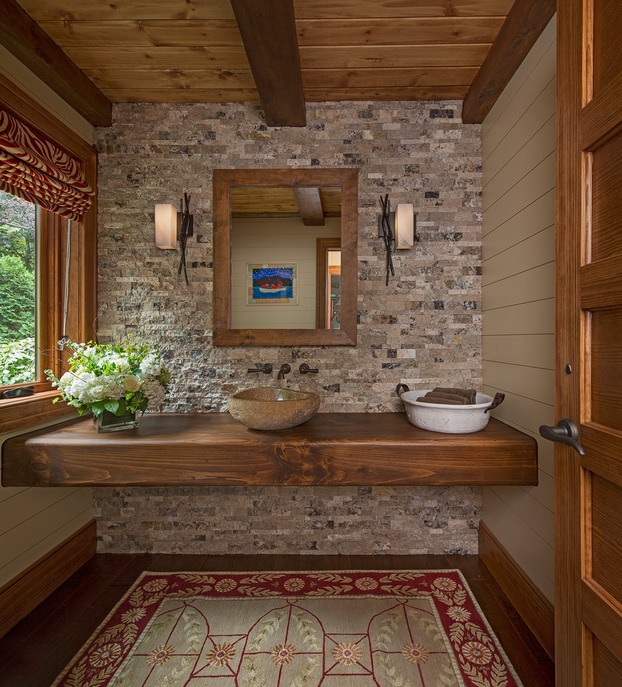 Aménagement d'une salle de bain classique en bois brun avec un placard sans porte, un carrelage beige, un carrelage de pierre, un sol en bois brun, une vasque, un plan de toilette en bois et un sol marron.