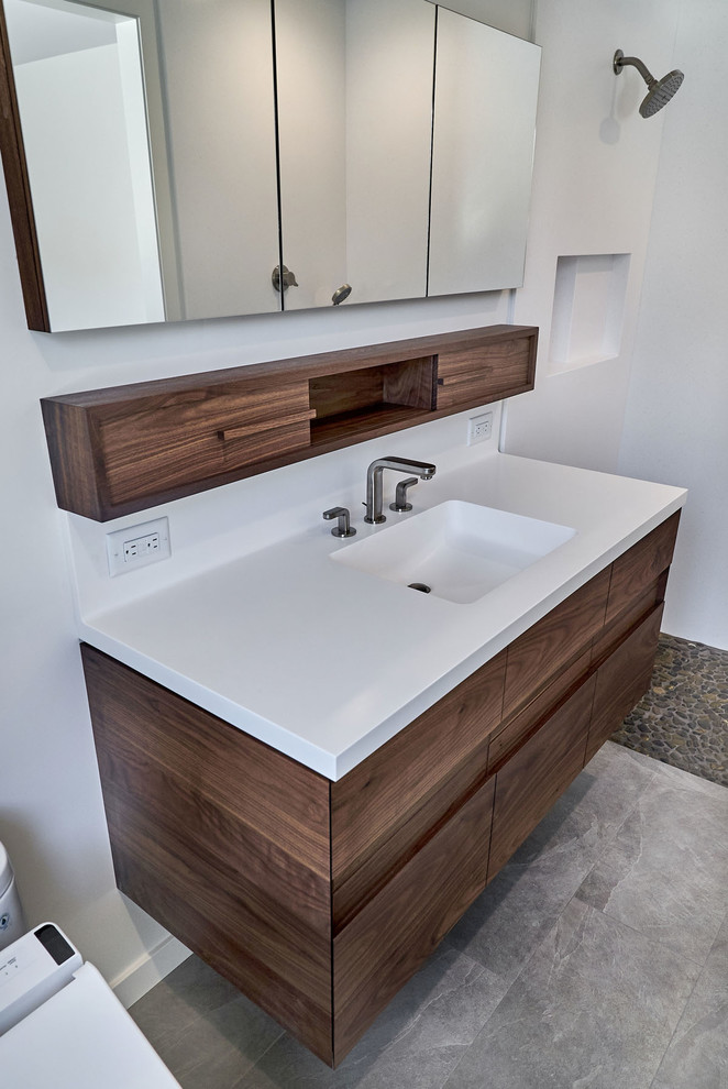 Inspiration for a medium sized modern ensuite bathroom in San Francisco with flat-panel cabinets, brown cabinets, an alcove shower, a one-piece toilet, white tiles, stone slabs, white walls, an integrated sink, engineered stone worktops and white worktops.