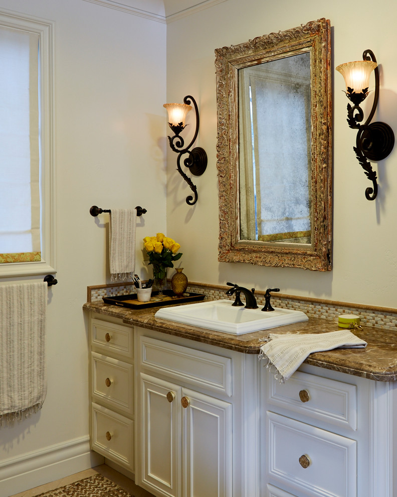 Example of a mid-sized transitional master multicolored tile and mosaic tile travertine floor drop-in bathtub design in San Francisco with recessed-panel cabinets, white cabinets, beige walls, a drop-in sink and marble countertops