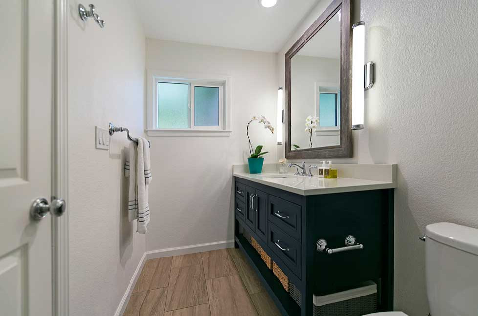 Exemple d'une petite salle de bain chic avec un placard avec porte à panneau encastré, des portes de placard bleues, WC séparés, un mur blanc, un sol en carrelage de porcelaine, un lavabo encastré, un plan de toilette en quartz modifié, un sol marron, un plan de toilette blanc, meuble simple vasque et meuble-lavabo sur pied.