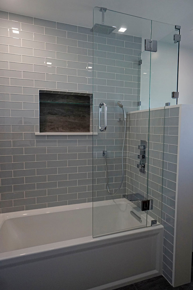Photo of a medium sized contemporary bathroom in Los Angeles with flat-panel cabinets, medium wood cabinets, an alcove bath, a one-piece toilet, blue tiles, glass tiles, grey walls, porcelain flooring, a trough sink, engineered stone worktops, grey floors, a hinged door and white worktops.