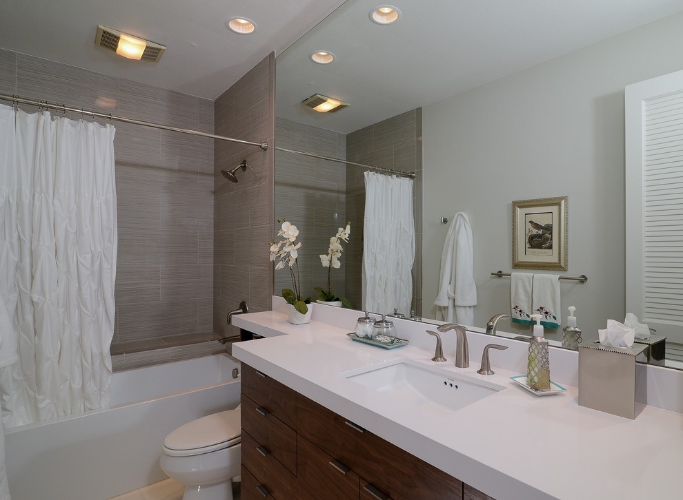 Diseño de cuarto de baño minimalista con lavabo bajoencimera, armarios con paneles lisos, puertas de armario de madera en tonos medios y combinación de ducha y bañera