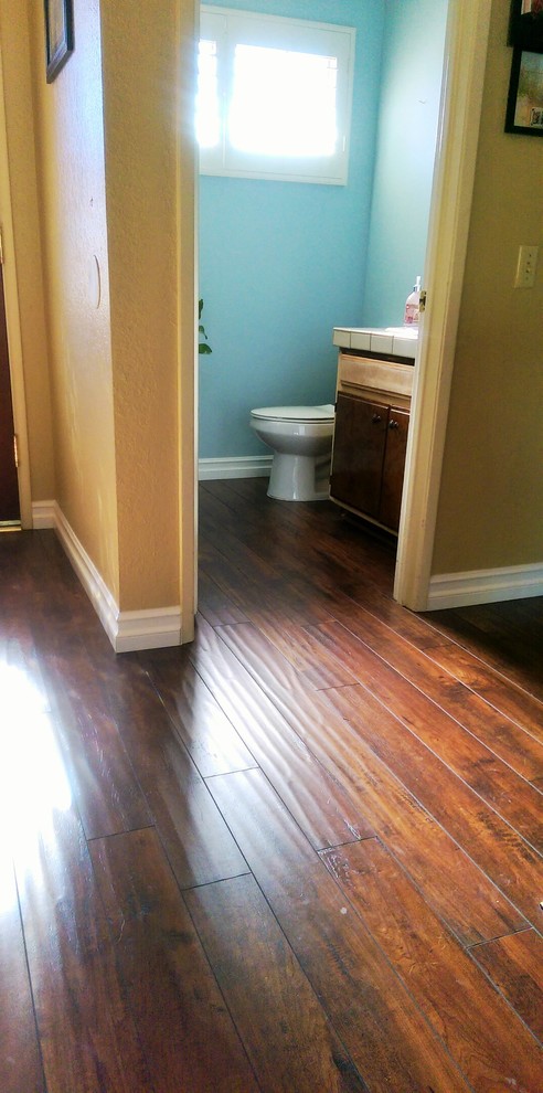 Example of a large mountain style 3/4 laminate floor and brown floor bathroom design in Los Angeles with dark wood cabinets, blue walls and tile countertops