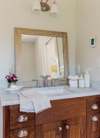 Ejemplo de cuarto de baño actual de tamaño medio con lavabo bajoencimera, armarios con paneles lisos, puertas de armario de madera en tonos medios y encimera de mármol