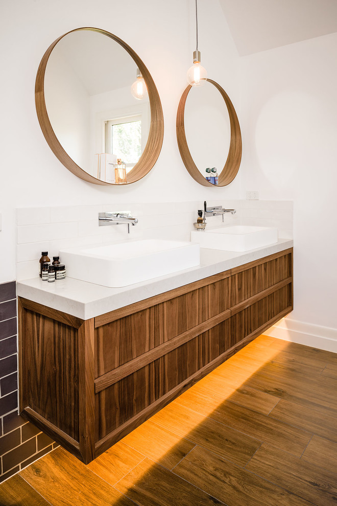 Modernes Badezimmer mit Aufsatzwaschbecken, hellbraunen Holzschränken, weißer Wandfarbe und braunem Holzboden in Melbourne
